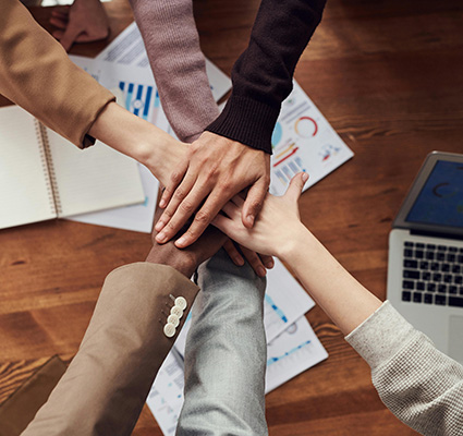 Decidewise community image joining hands at conference table.jpg